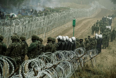 FILE PHOTO: Polish soldiers and police watch migrants at the Poland/Belarus border near Kuznica, Poland, in this photograph released by the Territorial Defence Forces, November 12, 2021.  Irek Dorozanski/DWOT/Handout via REUTERS