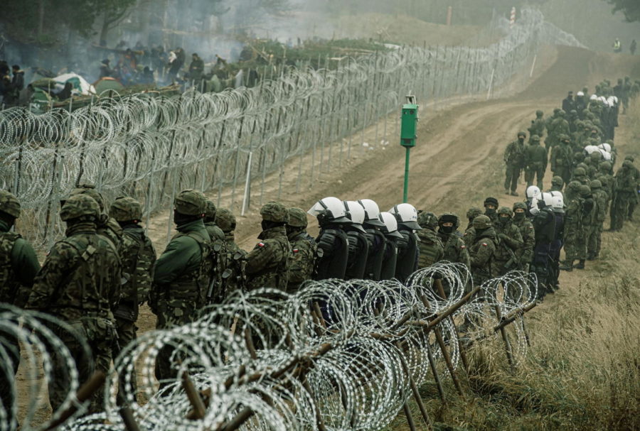 FILE PHOTO: Polish soldiers and police watch migrants at the Poland/Belarus border near Kuznica, Poland, in this photograph released by the Territorial Defence Forces, November 12, 2021.  Irek Dorozanski/DWOT/Handout via REUTERS